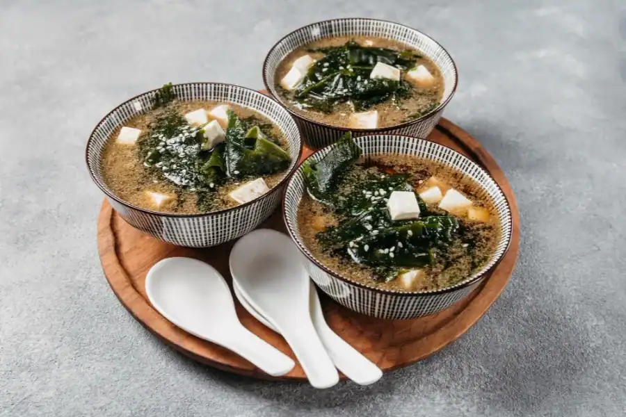 Bowls of miso soup with tofu, seaweed, and sesame seeds