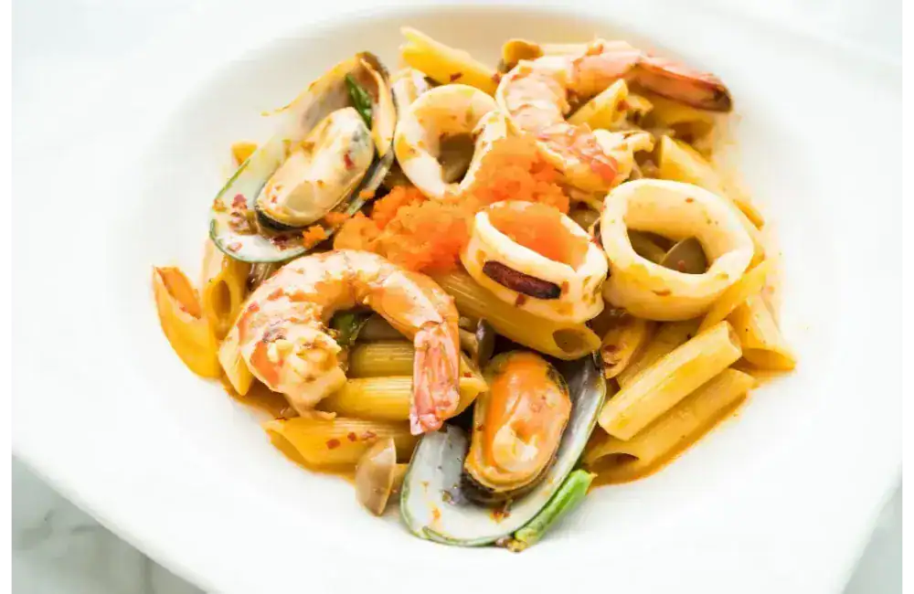 Close-up of squid pasta with shrimp, mussels, and penne in a spicy seafood sauce