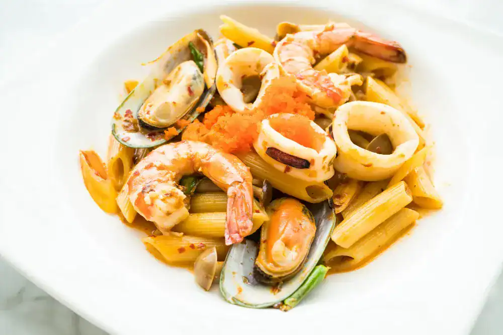 Close-up of squid pasta with shrimp, mussels, and penne in a spicy seafood sauce