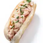 Classic East Coast lobster roll with creamy lobster filling and chopped chives on a split-top bun.