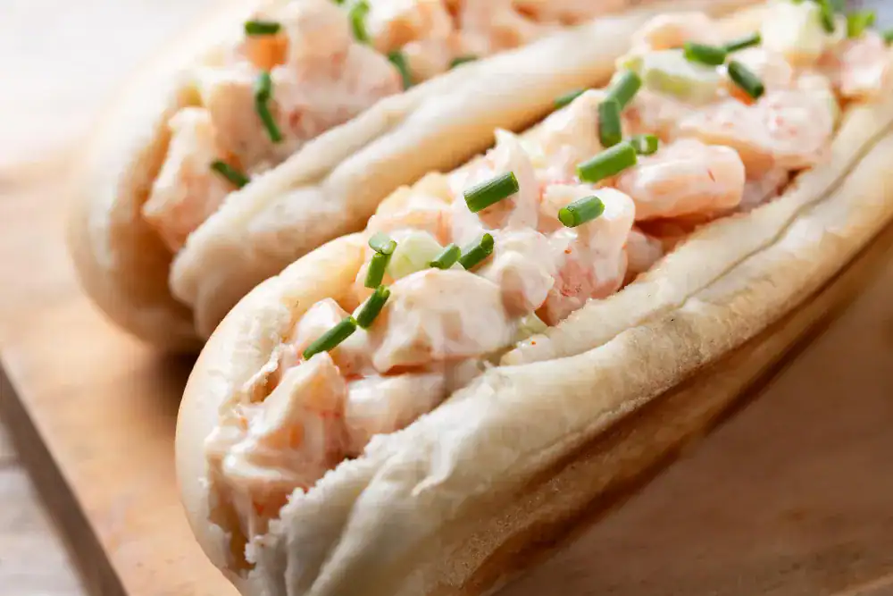 Close-up of a creamy lobster roll with fresh chives in a toasted split-top bun.