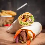 Close-up of homemade doner kebab wraps filled with grilled meat, fresh vegetables, and sauce
