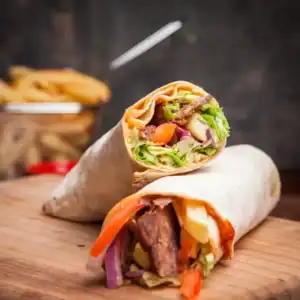 Close-up of homemade doner kebab wraps filled with grilled meat, fresh vegetables, and sauce
