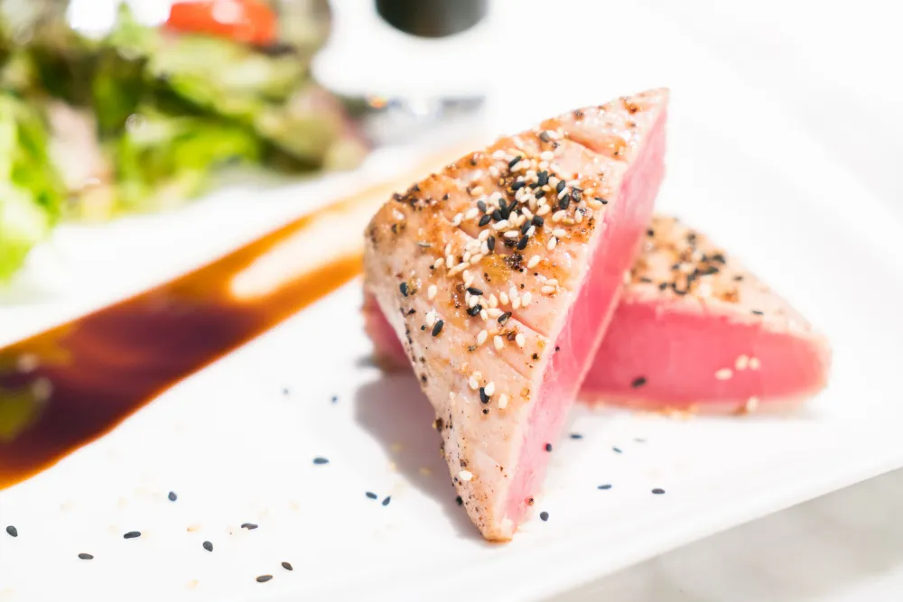 Sliced sesame-crusted tuna steak served rare with salad and soy glaze
