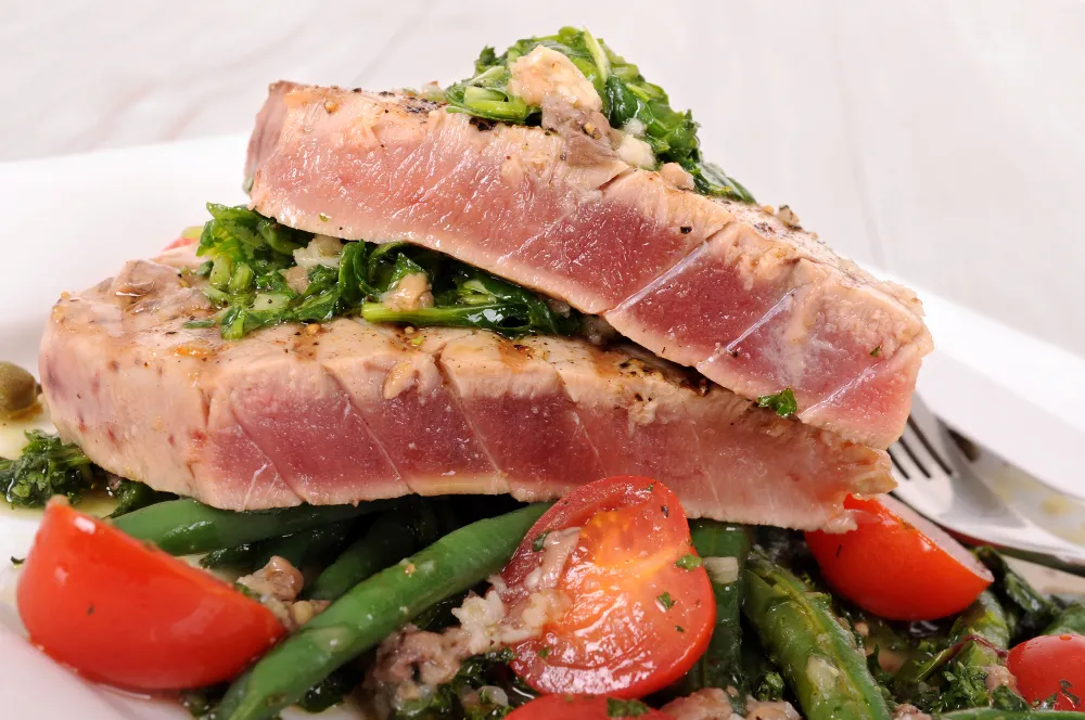 Seared tuna steaks served on sautéed greens with cherry tomatoes