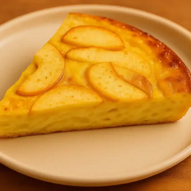 Single slice of apple frittata on a white plate with warm golden tones