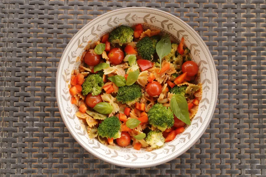 Colorful tuna pasta salad with broccoli, cherry tomatoes, bell pepper, and fresh basil