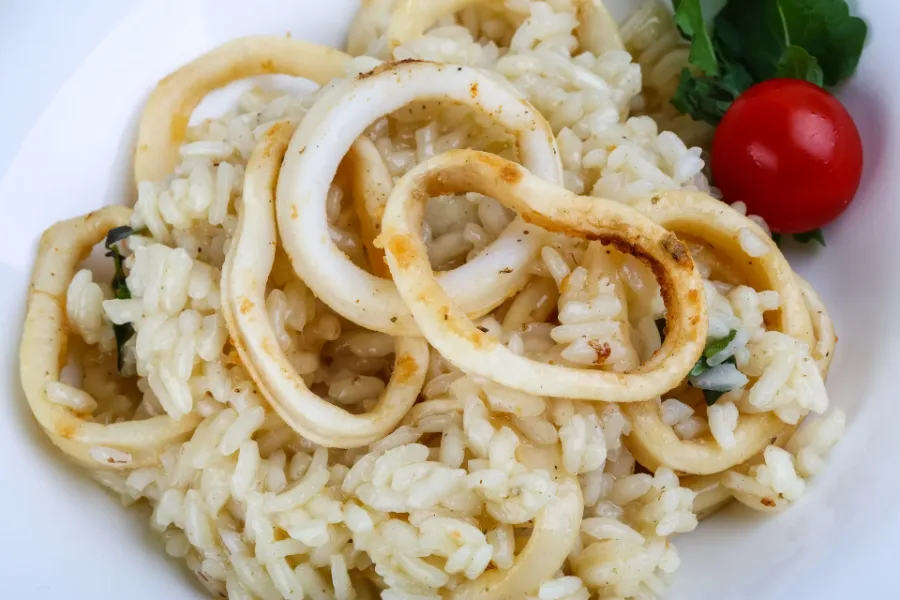 Grilled calamari rings served over creamy rice with a cherry tomato and herbs.