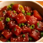A close-up bowl of fresh homemade ahi poke with marinated tuna cubes, green onions, and sesame seeds.