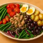 Authentic Niçoise salad with tuna, potatoes, eggs, olives, and vegetables served in an oval plate
