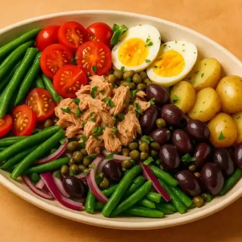 Authentic Niçoise salad with tuna, potatoes, eggs, olives, and vegetables served in an oval plate