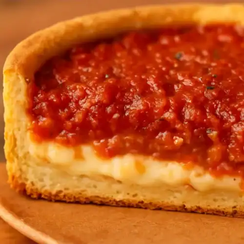 Close-up of a slice of Chicago-style deep dish pizza with thick crust, melted cheese, and chunky tomato sauce
