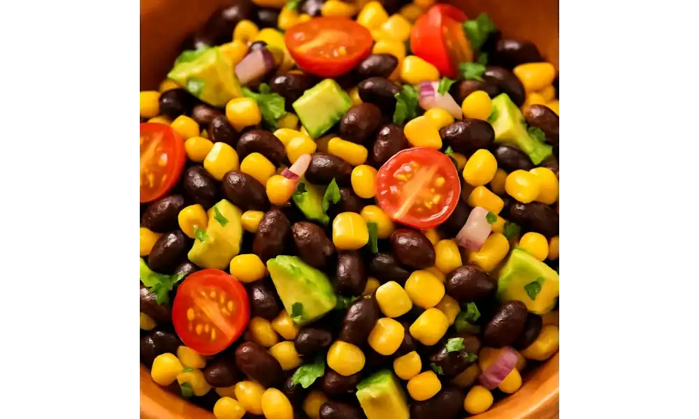 Close-up of black bean and corn salad with avocado, cherry tomatoes, red onion, and fresh cilantro.