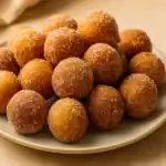 Plate of sugar-coated homemade donut holes on a neutral background