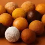 A variety of Dunkin’ donut holes arranged on a warm-toned surface, including glazed, powdered, chocolate, and cinnamon flavors.