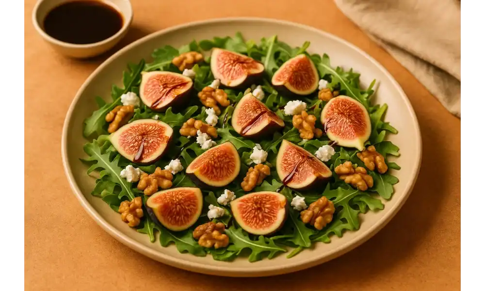 Fig salad with arugula, goat cheese, walnuts, and balsamic glaze on a ceramic plate with a small bowl of dressing