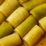 Close-up of tender braised leeks in a golden sauce with seasoning