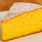 Close-up of a moist polenta cake slice topped with powdered sugar