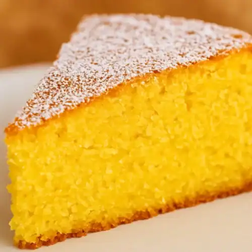 Close-up of a moist polenta cake slice topped with powdered sugar