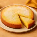 Golden polenta cake sliced and dusted with powdered sugar on a plate