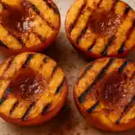Grilled peach halves with caramelized brown sugar and cinnamon on a plate.