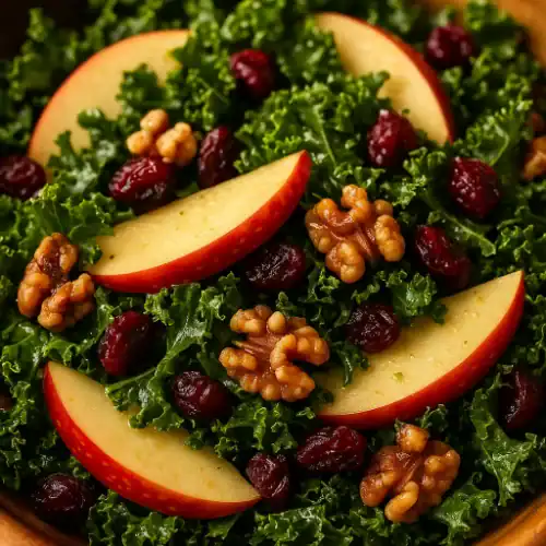 Close-up of kale apple walnut cranberry salad with crisp apple slices, dried cranberries, and toasted walnuts on fresh green kale leaves, lightly dressed in maple Dijon vinaigrette.