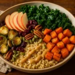 A warm fall harvest grain bowl filled with quinoa, roasted sweet potatoes, kale, Brussels sprouts, apples, pecans, cranberries, and pumpkin seeds drizzled with creamy maple-tahini dressing.