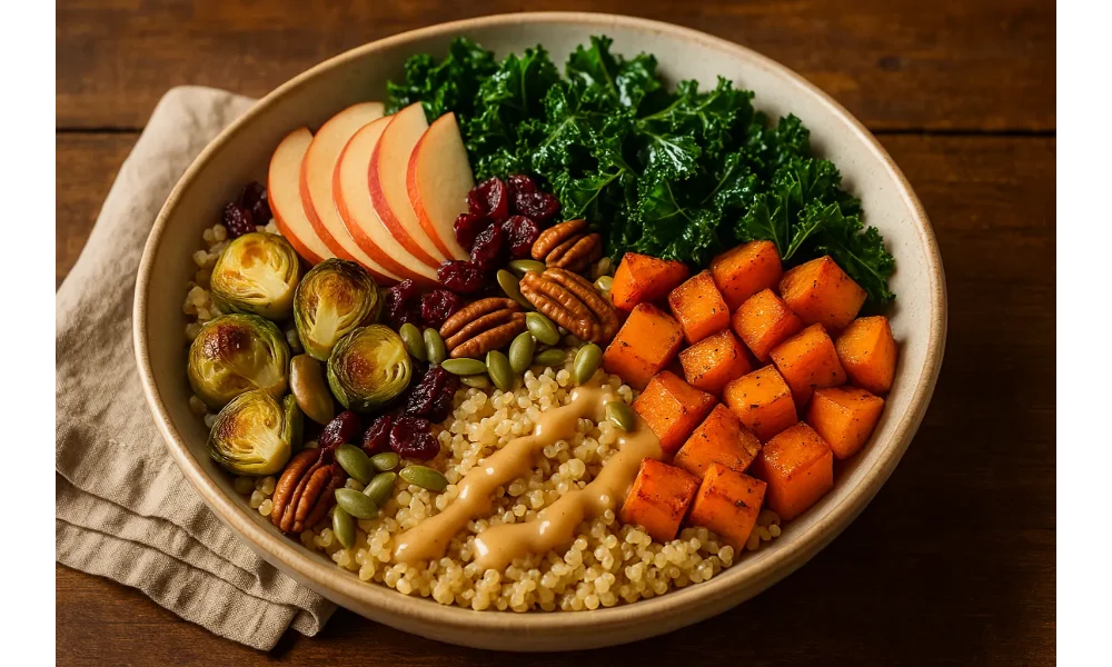 A warm fall harvest grain bowl filled with quinoa, roasted sweet potatoes, kale, Brussels sprouts, apples, pecans, cranberries, and pumpkin seeds drizzled with creamy maple-tahini dressing.