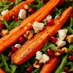Close-up of honey roasted carrot salad with feta, arugula, pomegranate seeds, and walnuts.