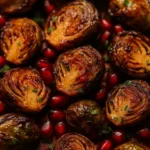 Close-up of roasted Brussels sprouts glazed with pomegranate molasses, garnished with fresh parsley and pomegranate seeds.